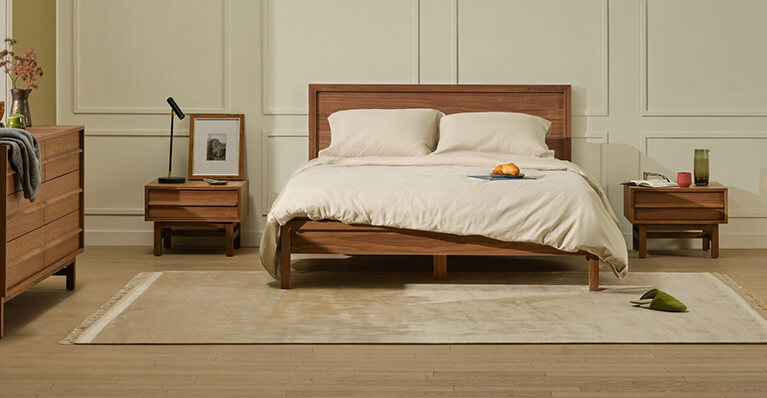 A queen walnut bed and matching storage is displayed in a modern bedroom. Link to bed category