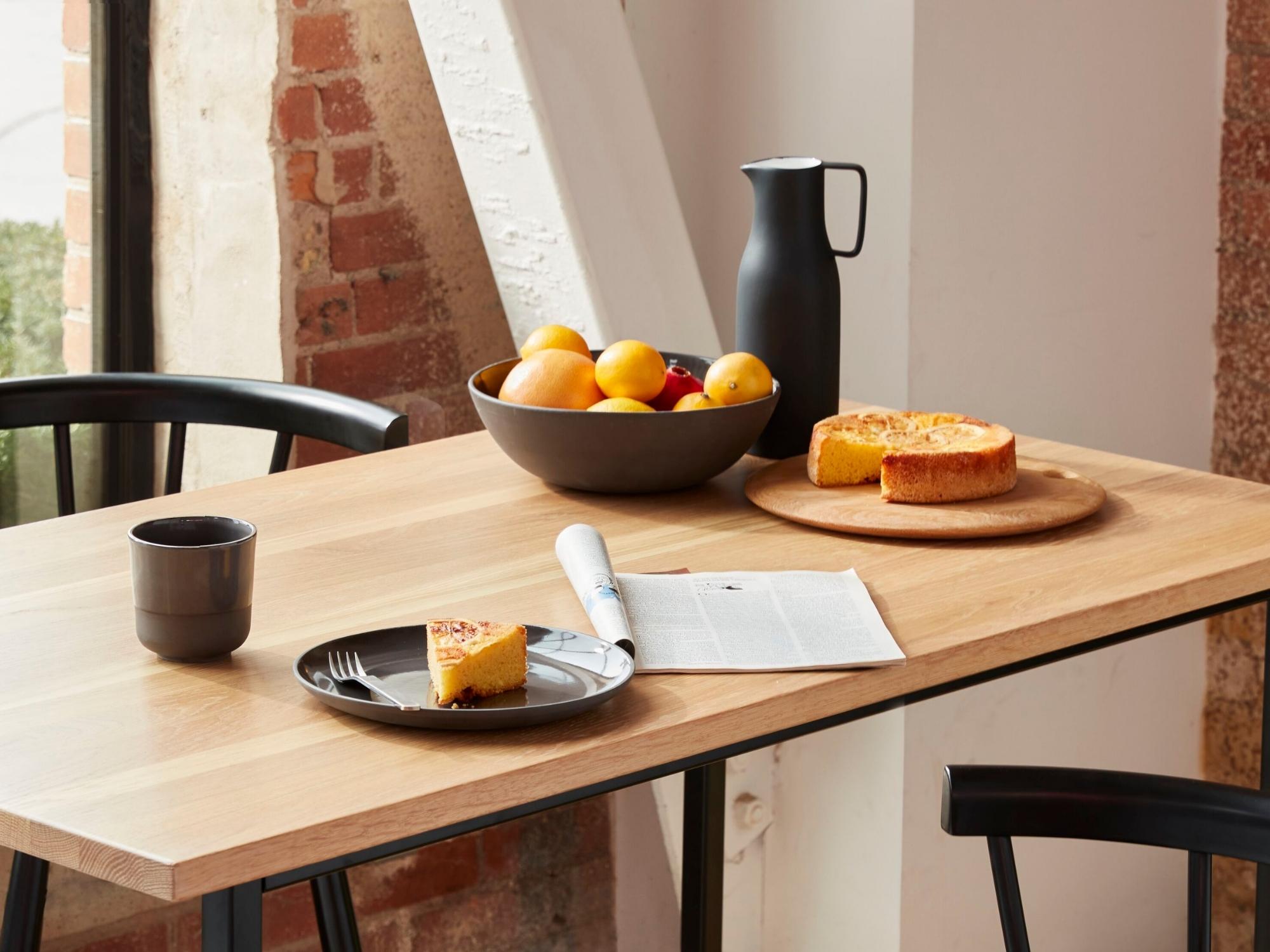 Black serving bowl on bar height table set for meal with bar stools